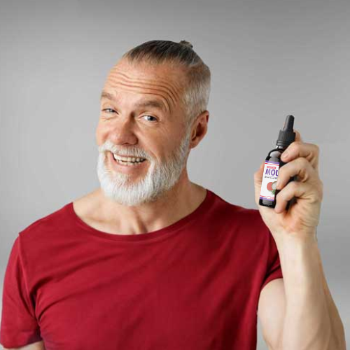 Man in red shirt and with beard holding a bottle of Mounja Burn Drops